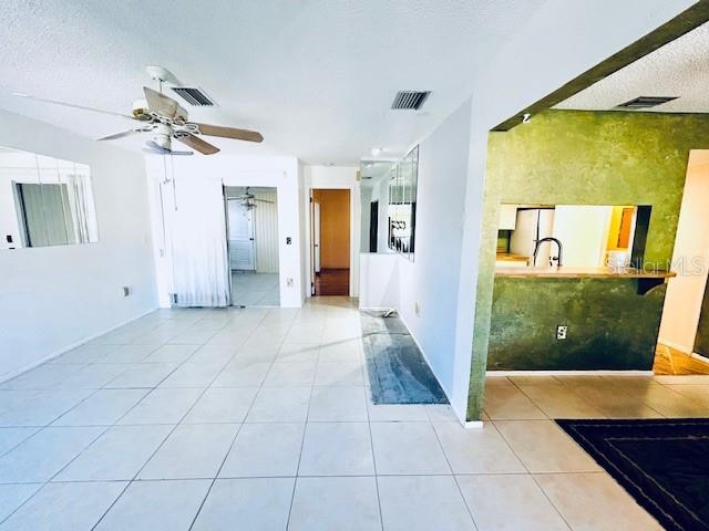 2607 29th Ave W, Bradenton, FL 34205 - unfurnished living room featuring tile patterned flooring, a ceiling fan, a textured ceiling, and baseboards