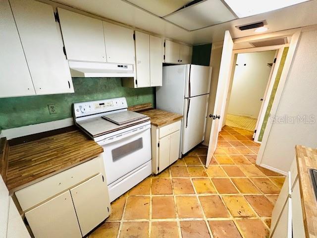2607 29th Ave W, Bradenton, FL 34205 - kitchen with under cabinet range hood, white appliances, light tile patterned flooring, and white cabinets