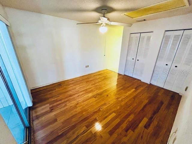 2607 29th Ave W, Bradenton, FL 34205 - unfurnished bedroom with wood finished floors, multiple closets, a textured ceiling, attic access, and a ceiling fan