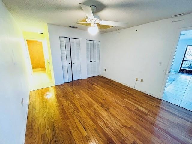 2607 29th Ave W, Bradenton, FL 34205 - unfurnished bedroom featuring wood finished floors, two closets, ceiling fan, and a textured ceiling