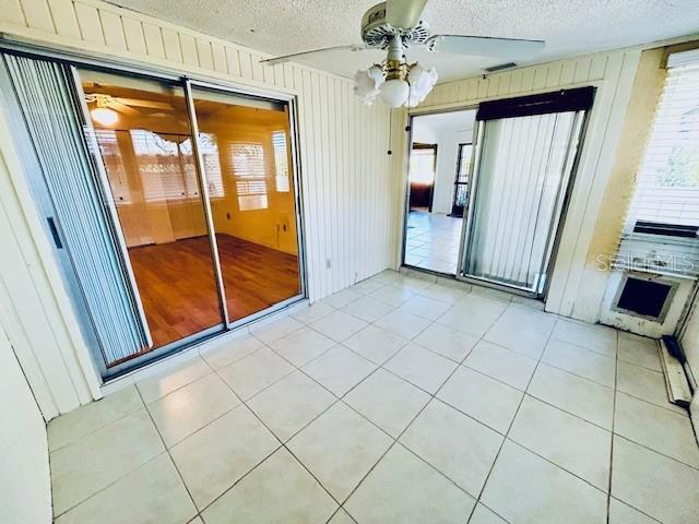 2607 29th Ave W, Bradenton, FL 34205 - tiled spare room featuring a textured ceiling, a ceiling fan, and wood walls