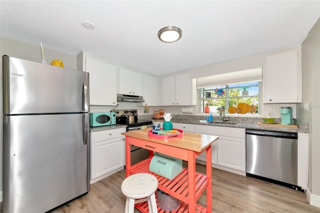 5948 Mirror Lake Rd, Sarasota, FL 34238 - kitchen featuring stainless steel appliances, under cabinet range hood, light wood-style flooring, and white cabinets