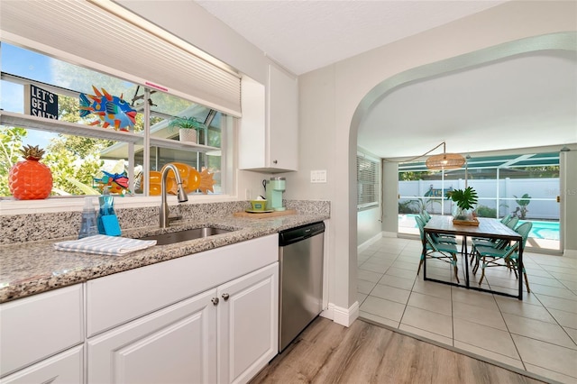 5948 Mirror Lake Rd, Sarasota, FL 34238 - kitchen with dishwasher, arched walkways, white cabinetry, and light stone countertops