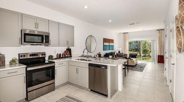 8697 Daybreak St, Sarasota, FL 34241 - kitchen with appliances with stainless steel finishes, a sink, a peninsula, gray cabinetry, and light countertops