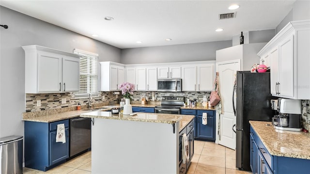 8804 Founders Cir, Palmetto, FL 34221 - kitchen featuring appliances with stainless steel finishes, blue cabinets, white cabinetry, light tile patterned floors, and tasteful backsplash