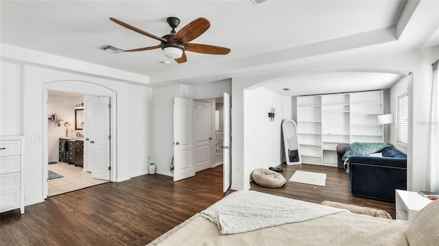 8804 Founders Cir, Palmetto, FL 34221 - bedroom featuring arched walkways, wood finished floors, ensuite bathroom, and ceiling fan