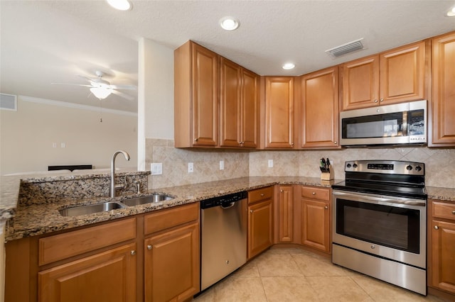 6923 Grand Estuary Trl Unit 101, Bradenton, FL 34212 - kitchen with appliances with stainless steel finishes, a ceiling fan, stone countertops, decorative backsplash, and light tile patterned flooring