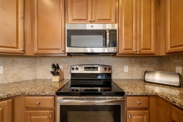 6923 Grand Estuary Trl Unit 101, Bradenton, FL 34212 - kitchen with stainless steel appliances, tasteful backsplash, and light stone countertops