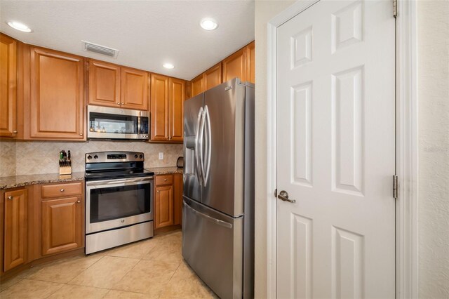 6923 Grand Estuary Trl Unit 101, Bradenton, FL 34212 - kitchen featuring appliances with stainless steel finishes, light tile patterned floors, light stone countertops, tasteful backsplash, and recessed lighting