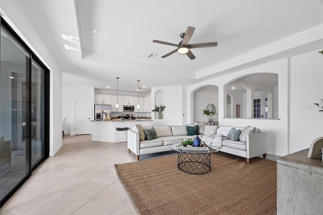 15344 Serene Shores Loop, Lakewood Ranch, FL 34211 - living room with light tile patterned flooring, a ceiling fan, a tray ceiling, recessed lighting, and arched walkways