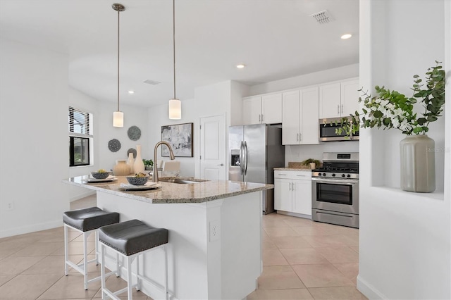 15344 Serene Shores Loop, Lakewood Ranch, FL 34211 - kitchen with stainless steel appliances, light tile patterned flooring, white cabinetry, light stone counters, and recessed lighting