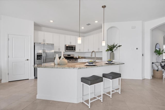 15344 Serene Shores Loop, Lakewood Ranch, FL 34211 - kitchen featuring stainless steel appliances, arched walkways, light tile patterned flooring, light stone counters, and recessed lighting