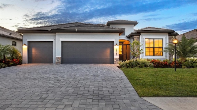 15344 Serene Shores Loop, Lakewood Ranch, FL 34211 - prairie-style house featuring a garage, decorative driveway, a lawn, stucco siding, and stone siding