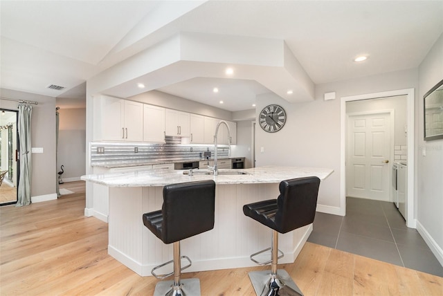 4353 Indian Point Trl, Sarasota, FL 34238 - kitchen featuring white cabinets, tasteful backsplash, a kitchen bar, recessed lighting, and light stone counters