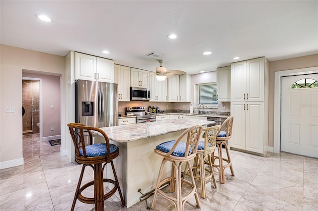 14544 Riverside Dr, Fort Myers, FL 33905 - kitchen featuring stainless steel appliances, light marble finish flooring, a kitchen bar, a center island, and recessed lighting