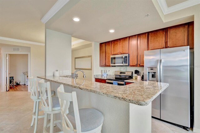 5528 Palmer Cir Unit 104, Bradenton, FL 34211 - kitchen with stainless steel appliances, light stone countertops, brown cabinetry, a peninsula, and a breakfast bar