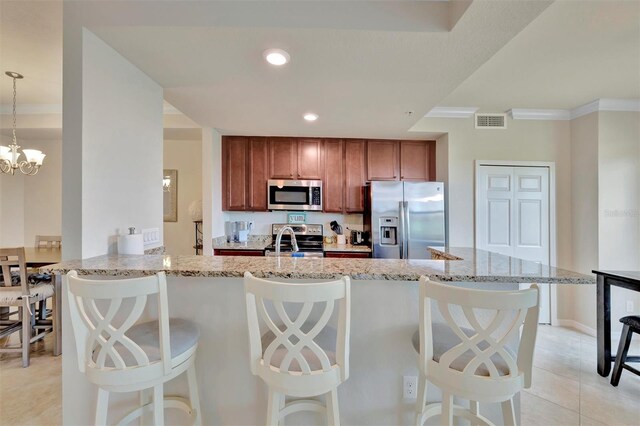 5528 Palmer Cir Unit 104, Bradenton, FL 34211 - kitchen with appliances with stainless steel finishes, ornamental molding, brown cabinets, light stone countertops, and a breakfast bar