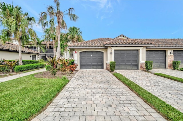 5528 Palmer Cir Unit 104, Bradenton, FL 34211 - view of front facade featuring stucco siding, a tile roof, decorative driveway, a front yard, and stone siding