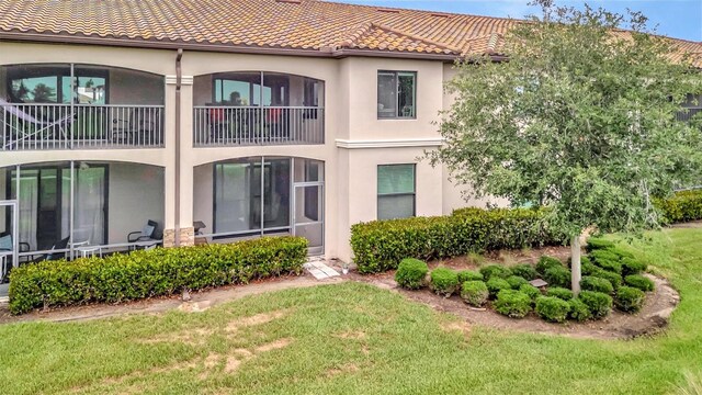 5528 Palmer Cir Unit 104, Bradenton, FL 34211 - back of house featuring stucco siding, a tile roof, and a lawn