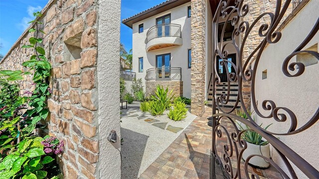795 Marbury Ln, Longboat Key, FL 34228 - property entrance with a balcony, stucco siding, french doors, and stone siding