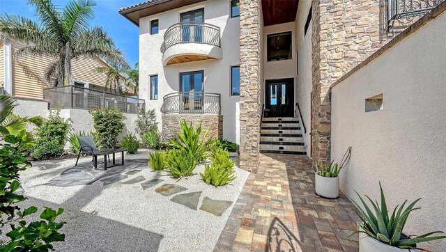 795 Marbury Ln, Longboat Key, FL 34228 - property entrance featuring stucco siding, stone siding, a balcony, and french doors
