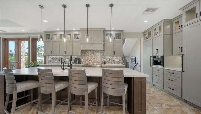 795 Marbury Ln, Longboat Key, FL 34228 - kitchen featuring recessed lighting, decorative backsplash, a center island with sink, stone tile floors, and cooktop