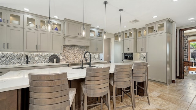 795 Marbury Ln, Longboat Key, FL 34228 - kitchen featuring gray cabinets, recessed lighting, decorative backsplash, light stone counters, and a center island with sink