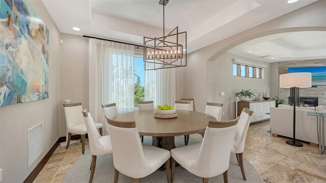 795 Marbury Ln, Longboat Key, FL 34228 - dining room featuring a tray ceiling, arched walkways, stone tile flooring, a chandelier, and recessed lighting