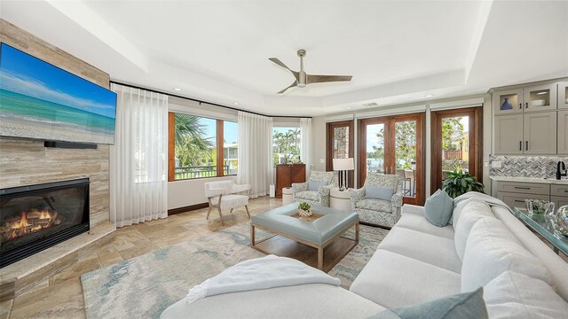 795 Marbury Ln, Longboat Key, FL 34228 - living area with a tray ceiling, a ceiling fan, stone tile floors, a tiled fireplace, and recessed lighting