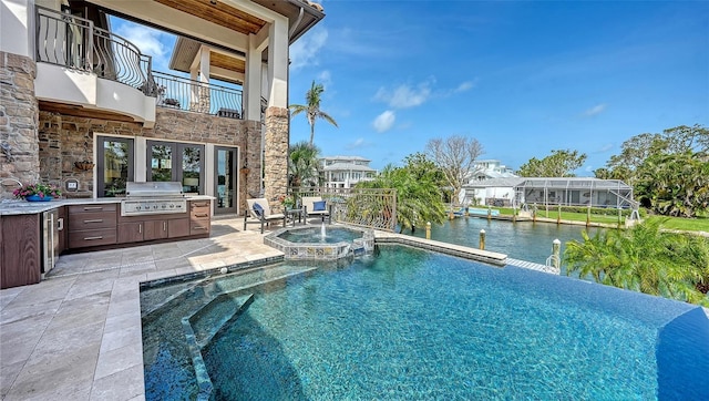 795 Marbury Ln, Longboat Key, FL 34228 - view of swimming pool featuring exterior kitchen, a patio area, a pool with connected hot tub, and a water view