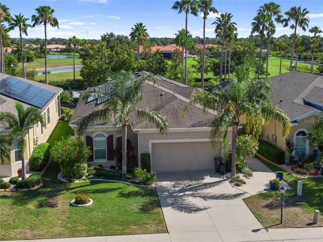 305 Siena Vista Pl, Sun City Center, FL 33573 - view of front facade with stucco siding, a water view, an attached garage, concrete driveway, and a front lawn