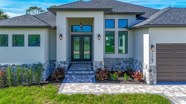 1167 Boundary Blvd, Rotonda West, FL 33947 - view of exterior entry with french doors, stone siding, stucco siding, and a garage