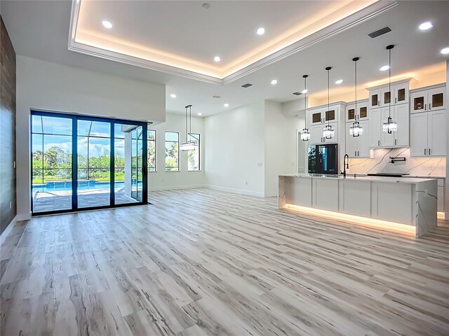 1167 Boundary Blvd, Rotonda West, FL 33947 - unfurnished living room featuring light wood-type flooring, recessed lighting, and a tray ceiling
