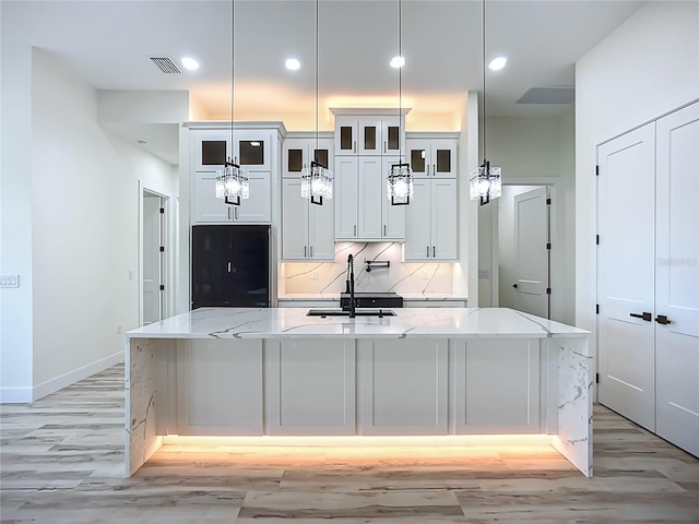 1167 Boundary Blvd, Rotonda West, FL 33947 - kitchen featuring light wood-style flooring, refrigerator, a large island with sink, light stone counters, and white cabinets
