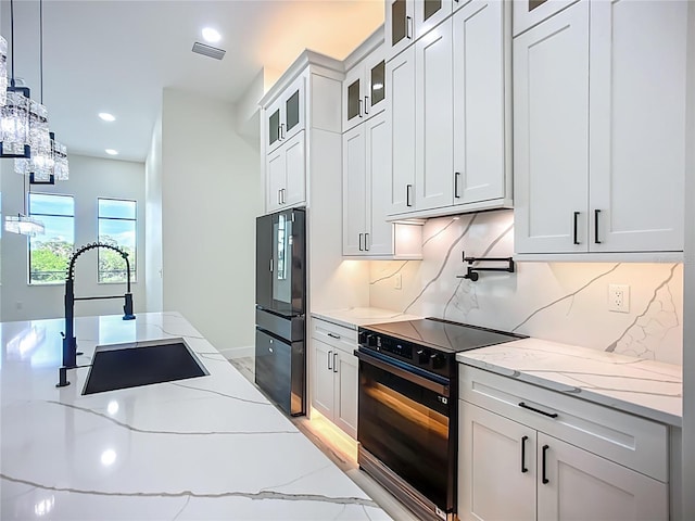 1167 Boundary Blvd, Rotonda West, FL 33947 - kitchen with black electric range, refrigerator, backsplash, white cabinets, and light stone countertops