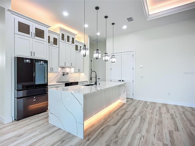 1167 Boundary Blvd, Rotonda West, FL 33947 - kitchen with refrigerator, an island with sink, light wood-type flooring, pendant lighting, and recessed lighting