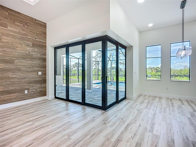 1167 Boundary Blvd, Rotonda West, FL 33947 - doorway featuring wood walls, wood finished floors, an accent wall, a chandelier, and recessed lighting
