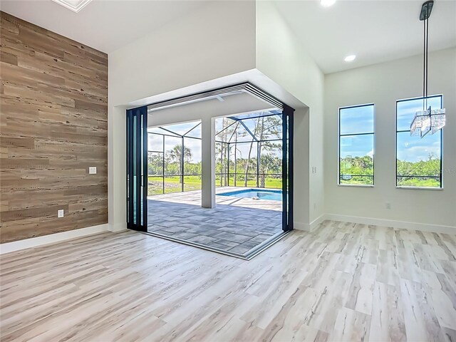 1167 Boundary Blvd, Rotonda West, FL 33947 - doorway to outside featuring a sunroom, wooden walls, light wood finished floors, recessed lighting, and a chandelier