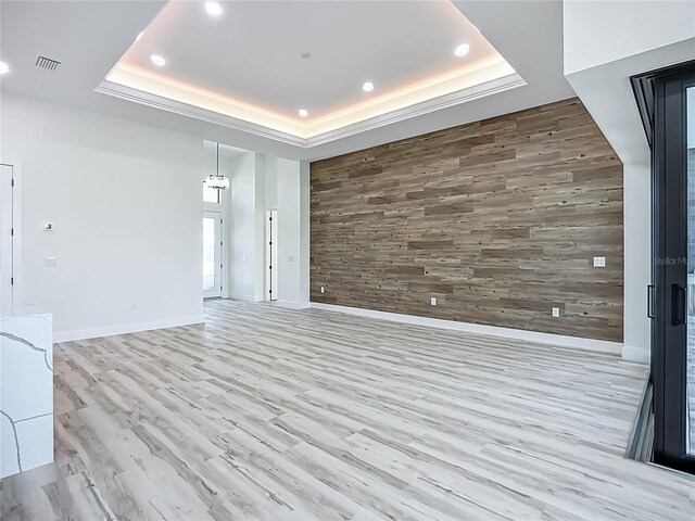 1167 Boundary Blvd, Rotonda West, FL 33947 - unfurnished living room featuring wooden walls, an accent wall, recessed lighting, a tray ceiling, and wood finished floors