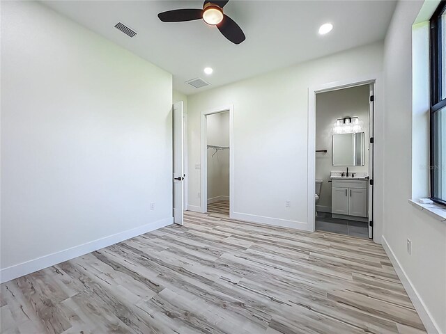 1167 Boundary Blvd, Rotonda West, FL 33947 - unfurnished bedroom with light wood-style flooring, ensuite bathroom, recessed lighting, a walk in closet, and ceiling fan