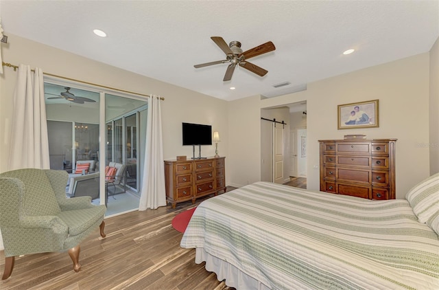 7302 Dunes Ct, Bradenton, FL 34202 - bedroom featuring access to exterior, a barn door, wood finished floors, ceiling fan, and recessed lighting