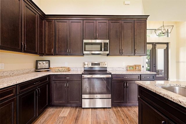 16630 Willow Point Ct, Alva, FL 33920 - kitchen featuring stainless steel appliances, dark brown cabinetry, light stone countertops, and light wood-type flooring