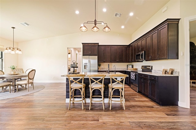 16630 Willow Point Ct, Alva, FL 33920 - kitchen featuring appliances with stainless steel finishes, dark brown cabinets, a breakfast bar area, hanging light fixtures, and light wood finished floors