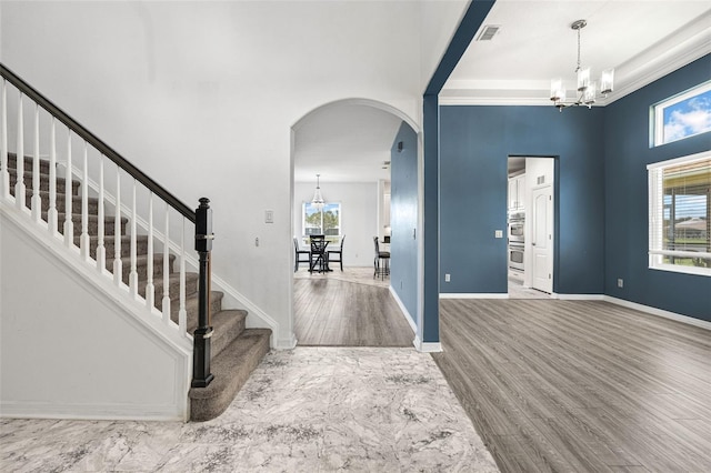2347 123rd Pl E, Parrish, FL 34219 - foyer featuring arched walkways, a chandelier, stairway, wood finished floors, and crown molding