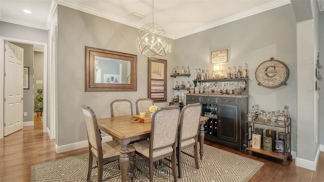 13220 Swiftwater Way, Lakewood Ranch, FL 34211 - dining area with a bar, dark wood-style flooring, ornamental molding, and a chandelier