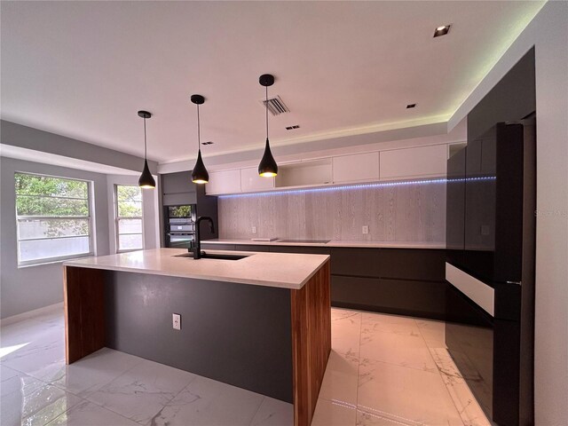 5848 Milton Ave, Sarasota, FL 34243 - kitchen with modern cabinets, light marble finish flooring, an island with sink, tasteful backsplash, and pendant lighting