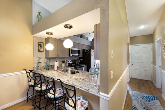 2904 64th St W Unit 2904, Bradenton, FL 34209 - kitchen with appliances with stainless steel finishes, light wood-type flooring, decorative backsplash, a breakfast bar area, and gray cabinets