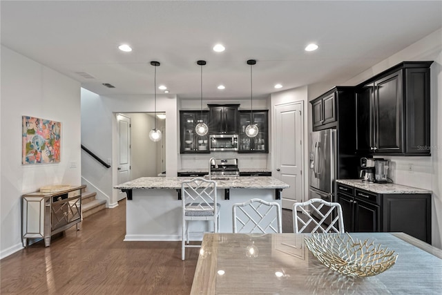 11434 Spring Gate Trl, Bradenton, FL 34211 - kitchen featuring stainless steel appliances, dark cabinetry, a kitchen breakfast bar, dark wood-style floors, and a center island with sink