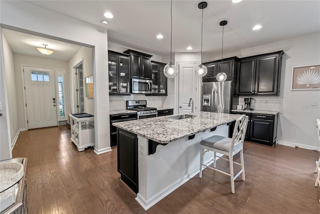 11434 Spring Gate Trl, Bradenton, FL 34211 - kitchen with appliances with stainless steel finishes, dark cabinetry, glass insert cabinets, a kitchen bar, and recessed lighting