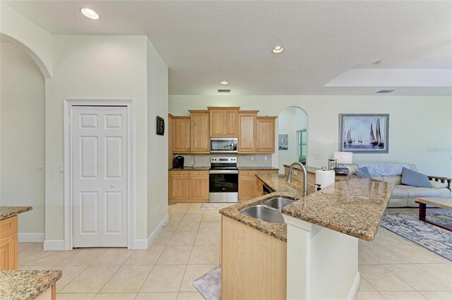 208 147th St NE, Bradenton, FL 34212 - kitchen featuring appliances with stainless steel finishes, arched walkways, light tile patterned floors, open floor plan, and light stone countertops